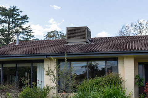 An evaporative cooler on the roofline of an Australian home seen from the front garden
