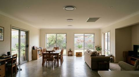 Three round ceiling diffusers evenly spaced along the centre of an open-plan Australian living area, with a larger rectangular return air grille set into the same ceiling